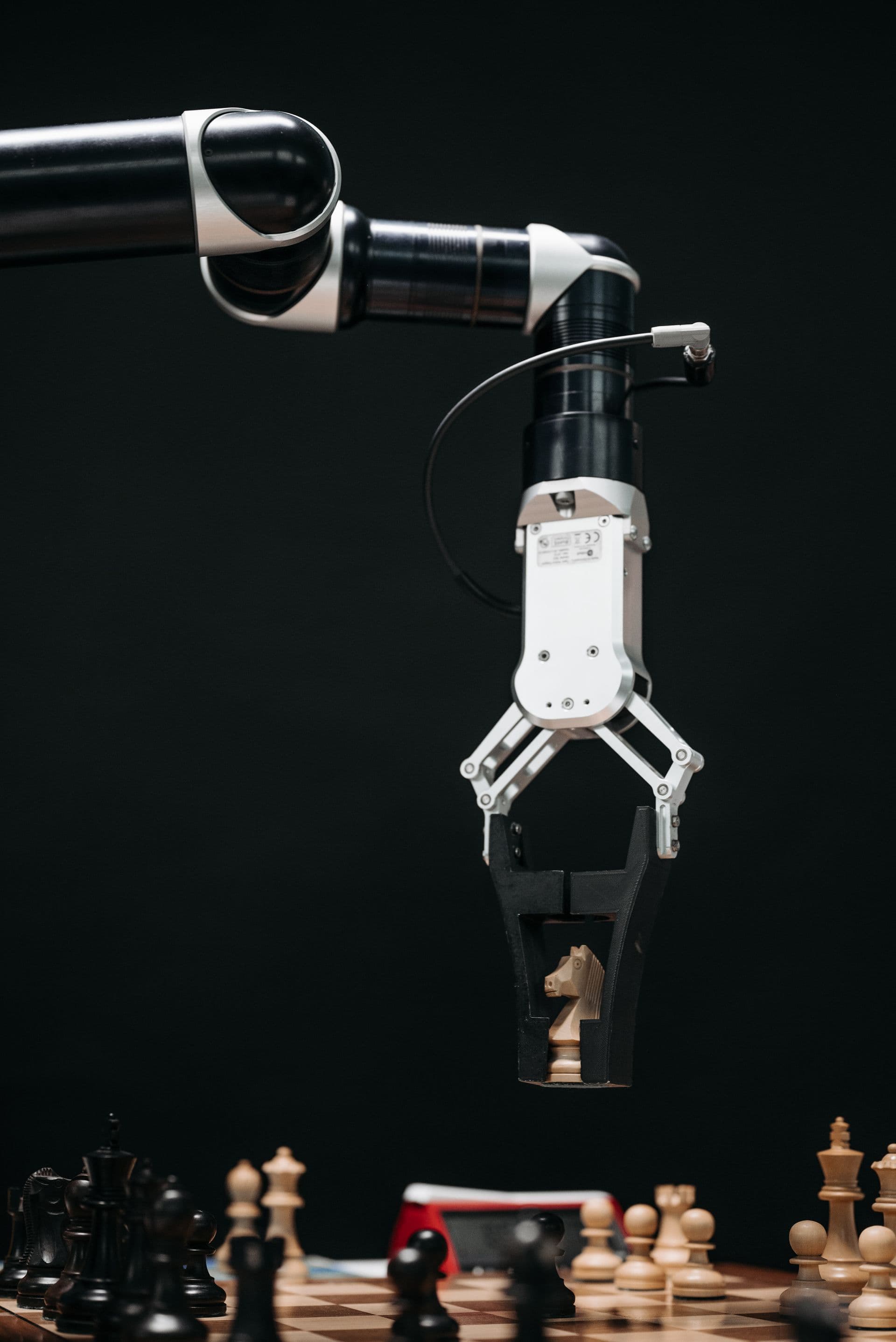 Robotic arm gripping a chess knight above a chessboard